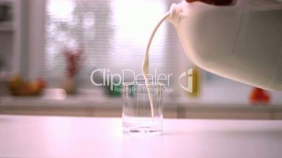 Milk pouring into small glass in kitchen