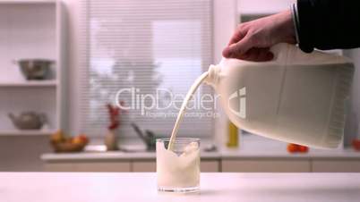 Man pouring milk into glass in kitchen