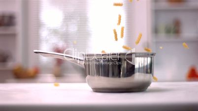 Fusilli falling into a saucepan in kitchen