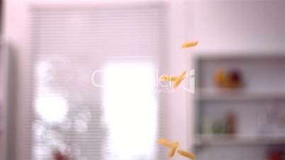 Penne falling into pot in kitchen