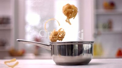 Tagliatelle falling into pot in kitchen