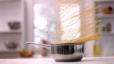 Spaghetti falling in pot in kitchen