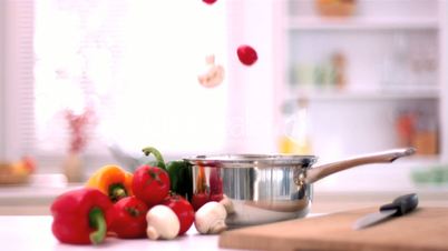 Cherry tomatoes and mushrooms falling in pot in kitchen