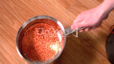 Man shaking red lentils in pot