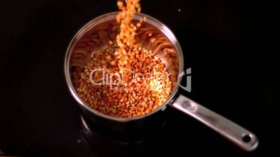 Popcorn pouring into pot on black background