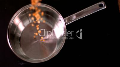 Popcorn pouring in pot on black background