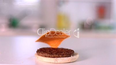 Cheese falling on bun burger in kitchen