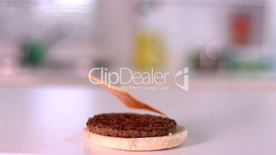 Slice of cheese falling on bun burger in kitchen