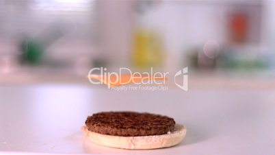 Slice of cheese falling on bun burger in the kitchen