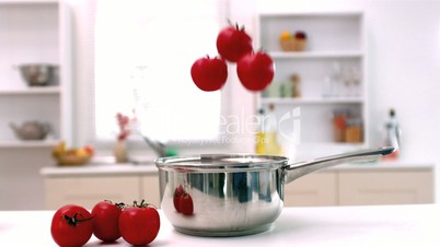 Tomatoes falling into pot in kitchen