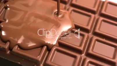 Melted chocolate being poured over a bar of chocolate