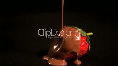 Melted chocolate pouring over a strawberry