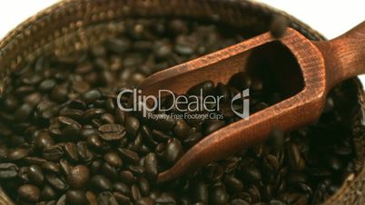 Coffee beans falling into basket with wooden scooper