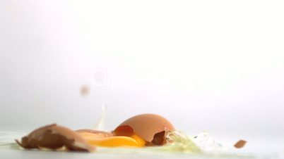 Egg breaking onto white surface