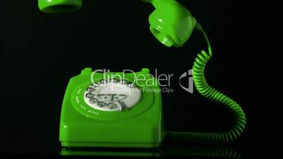 Receiver falling on green dial phone on black background