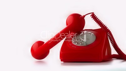 Receiver falling onto a red dial phone on white background