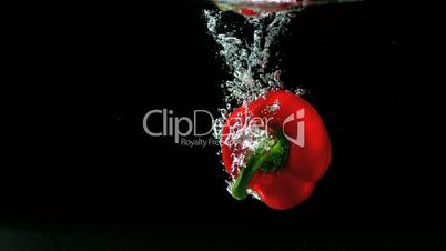 Red pepper falling in water and floating