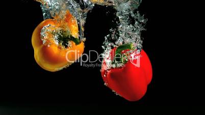 Two peppers falling in water and floating