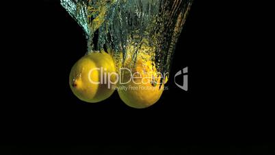 Two lemons dropping into water