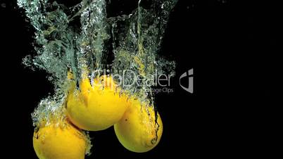 Pair of lemons dropping into water