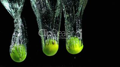 Three limes falling into water and floating