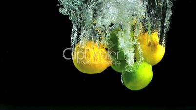 Lemons and limes dropping into water