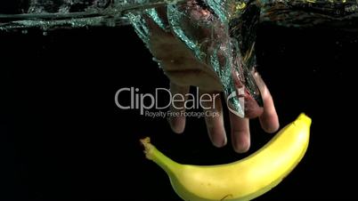 Hand taking banana from water