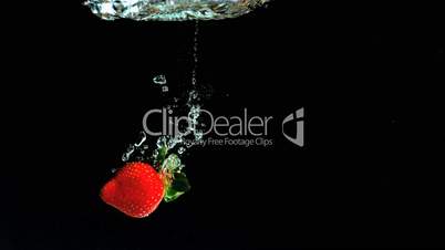 Strawberry falling into water and floating