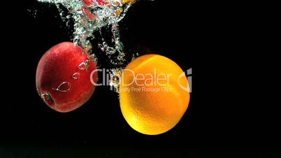 Apple and orange falling in water