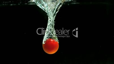 Tomato falling into water and floating