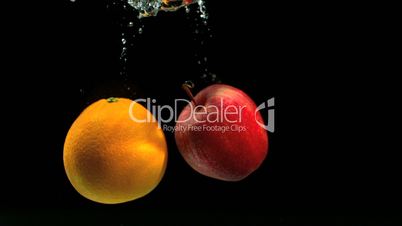 Orange and apple falling in water