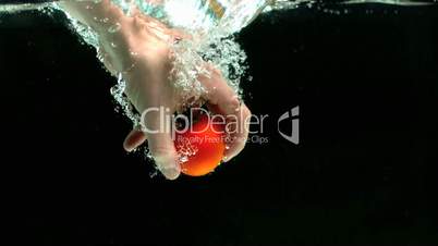 Hand grabbing tomato from water