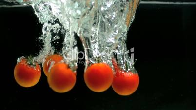 Five tomatoes falling in water