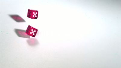 Pink dice rolling across white surface