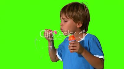 Boy blowing bubbles on green screen