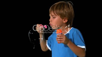 Boy blowing bubbles on black background