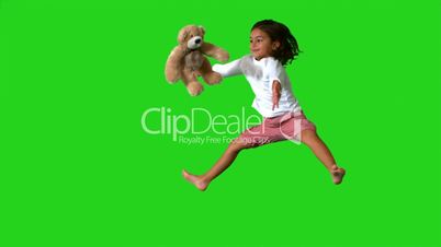 Little girl jumping on green screen and catching teddy