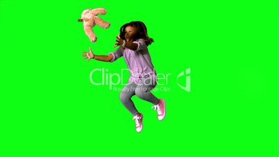 Happy little girl jumping up and catching teddy on green screen