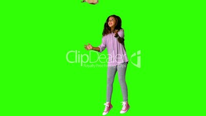 Happy little girl jumping up and catching teddy on the green screen