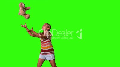 Girl jumping and catching teddy on a green screen