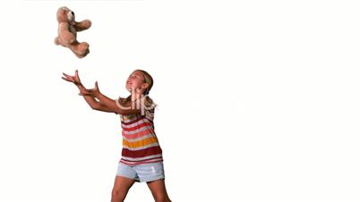 Girl jumping and catching teddy on a white background