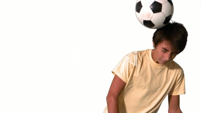 Boy heading a football on white background