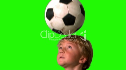 Little boy heading football on green screen