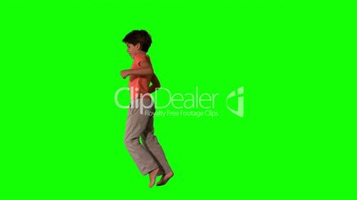 Side view of boy jumping up on green screen