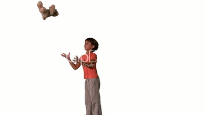 Side view of boy jumping and catching teddy on white background