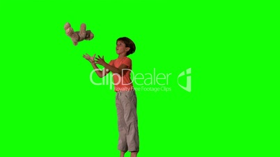 Side view of boy jumping and catching teddy on green screen