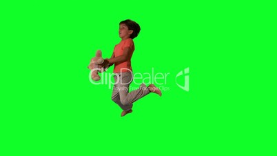 Side view of boy jumping up and catching teddy on green screen