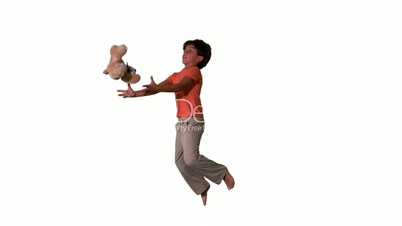 Side view of boy jumping up and catching teddy on white background