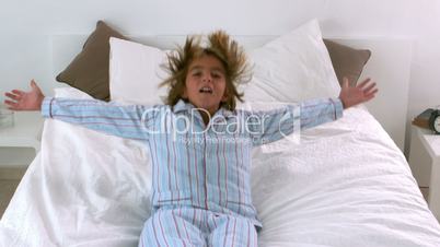 Little boy jumping back onto bed