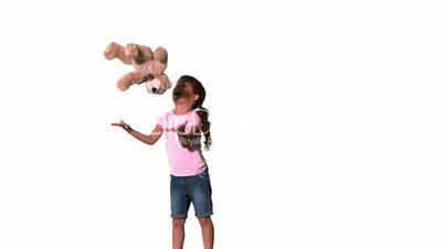 Cute little girl jumping and catching teddy on white background